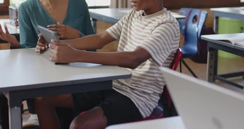 Using tablet together in school, teacher and student smiling and learning