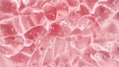 Gel cosmétique fluide rose transparent avec des bulles de molécules coulant sur la surface blanche