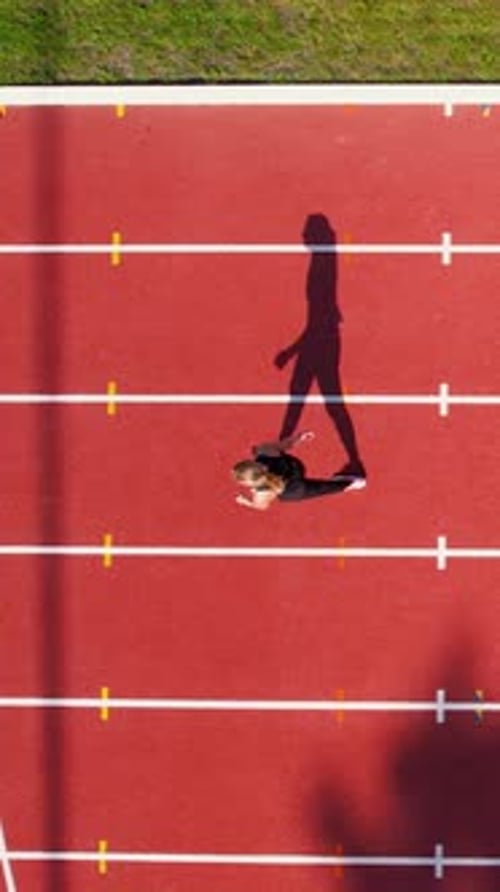 Aerial Top Down View Of Woman Running On Red Running Track