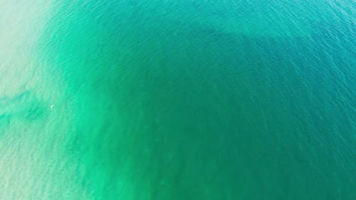 Luftbild von oben nach unten mit klarem Meerwasser und blauen und türkisfarbenen Wellen, die eine ruhige natürliche Kulisse bilden