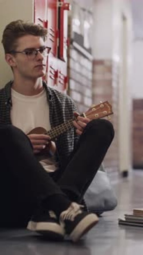 Bullying, education and guitar with student on floor of university corridor for music study
