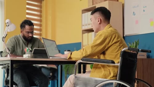 Young Man in Wheelchair Working on Laptop at Office