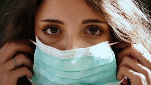 coronavirus - serious beautiful girl wears the mask looking at camera