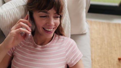 Woman Smiling and Talking on Phone Lying on Couch