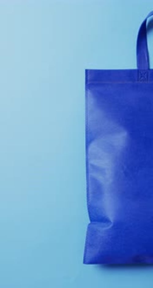 Vídeo vertical de bolsa de lona azul con espacio de copia sobre fondo azul