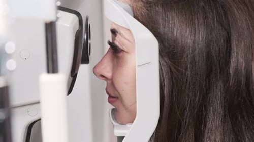 Attentive optometrist examining beautiful female patient with slit lamp in ophthalmology clinic. Opt