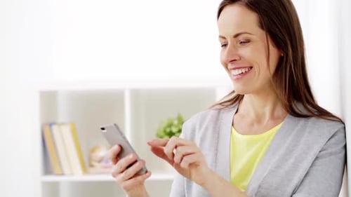 Smiling Woman Using Smartphone Indoors by White Wall