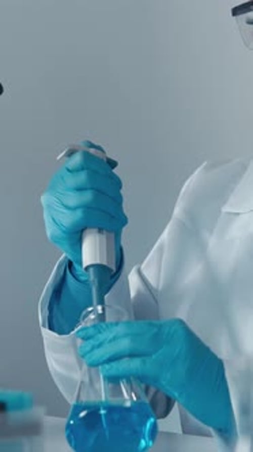Scientist Works with Pipette and Blue Liquid