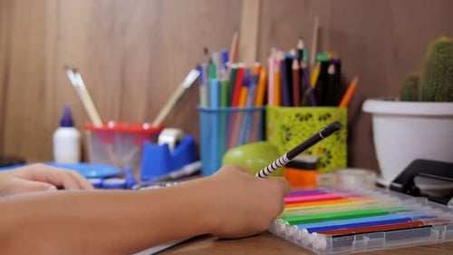Nahaufnahme eines kleinen Schülers, der in ein Notizbuch schreibt und zu Hause am Tisch sitzt