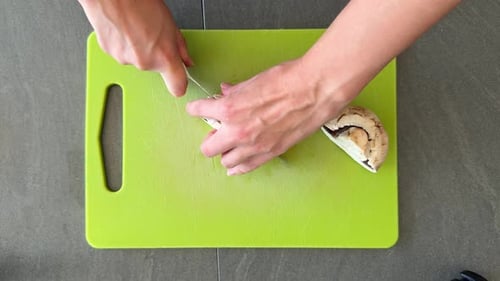 Top View of Woman Hands Finely Chopping Mushrooms with Knife During Food Preparation in Home Kitchen