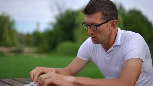 Handsome Man Thinking Sitting in Spring Summer Park Reading Smartphone Message Smiling