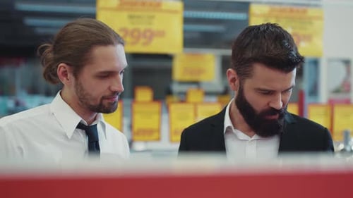 Attractive Seller Consultant Talk with Young Beard Man in Tech Store Business Hand Shopping