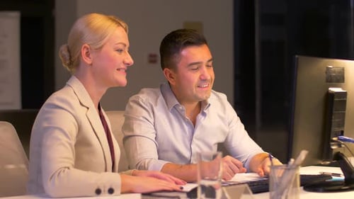 Smiling business team works late at night in a modern office with technology