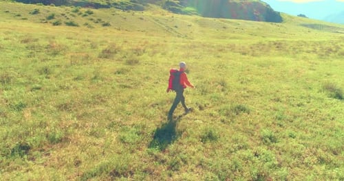 Flight Over Backpack Hiking Tourist Walking Across Green Mountain Field Huge Rural Valley at Summer