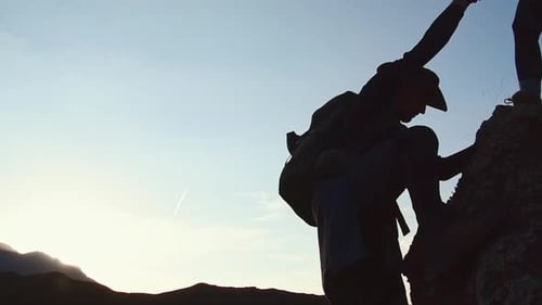Un randonneur donne un coup de main en grimpant au coucher du soleil Copie