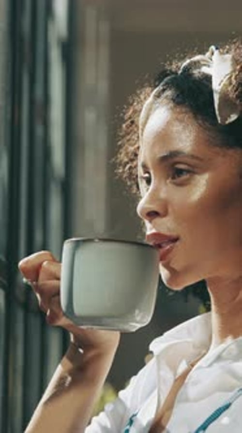 Woman Drinking a Hot Beverage by a Window