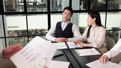 Professional business coworkers discussing reporting documents during a meeting in modern office cha