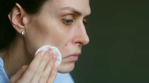 Woman Cleans Face with Cotton Pad Close Up