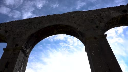Breached temple stone walls with arched windows on sky background, medieval architecture