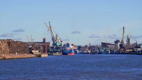 Vista em timelapse de guindastes portuários movimentados em funcionamento no porto de Liepaja, grandes navios de carga seca atracados, ensolarado d