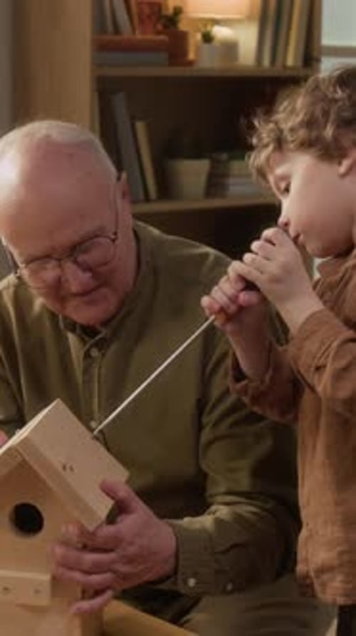 Abuelo y nieto construyen una pajarera de madera en casa