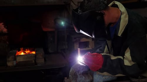A Handyman Performs Welding and Grinding at His Workplace in the Workshop