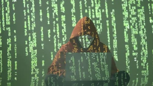 Hacker in Maske und Hoodie mit Laptop, umgeben von fallendem grünem Code in matrixähnlicher Umgebung