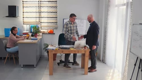 Architect and Manager Handshake in Office During Blueprint Discussion