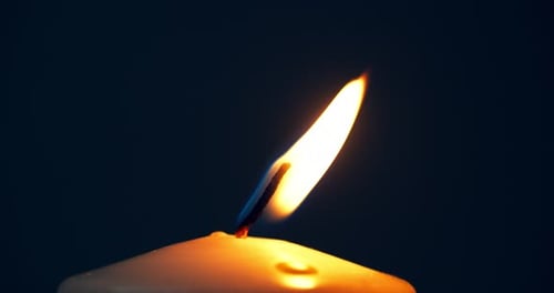 Eine einzelne große gelbe Kerzenflamme leuchtet und erlischt, isoliert auf schwarzem Hintergrund. Zeitlupe und