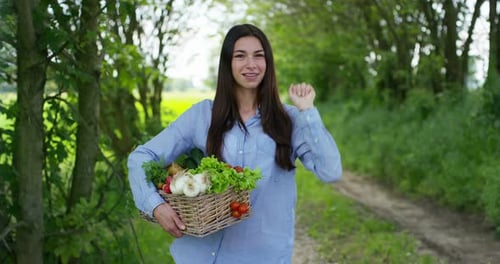 Beautiful young girl holding a basket of vegetables, in the background of nature. Concept: biology