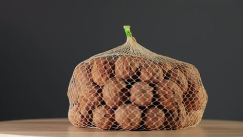 Whole Walnut in a Mesh Bag Rotating on Wooden Desk Closeup Walnuts in a Shell Healthy Snacks Product