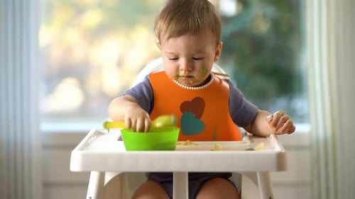 Infant Plays and Eats in High Chair
