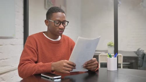 Young Adult Reads Documents in Office Workplace