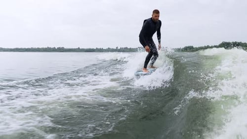 Man Wake Surfing on Lake on Overcast Day
