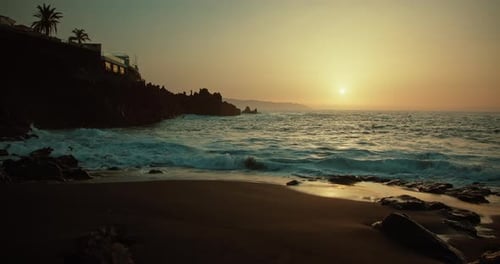 Ocean Waves Roll in Slowmotion on Black Sandy Smooth Beach at Sunset Sea Water Splashing at Dusk