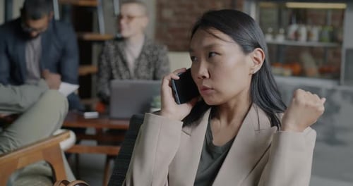 Happy Young Asian Woman Speaking on Mobile Phone Smiling Gesturing Discussing Business in Cafe