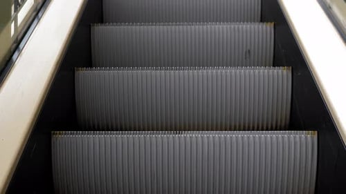 Moving Up Metal Escalator Steps in the Shopping Center