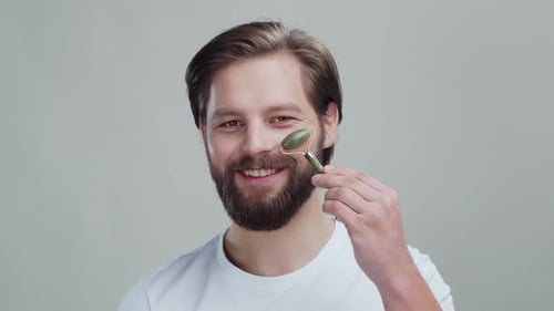 Bearded Man Using Jade Facial Roller on Face