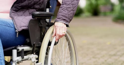 Woman propelling wheelchair outdoors