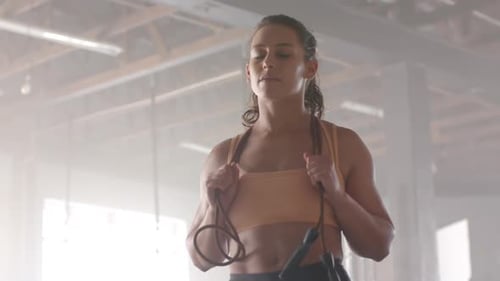 Holding jump rope, woman in gym wearing sports bra, ready for workout