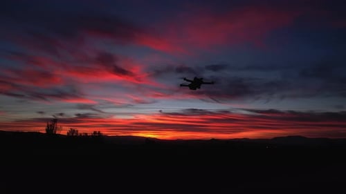 Drone in night flight with position lights flashing. Drone flying with colorful sky at sunset Aerial