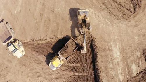 Excavator loading soil onto a Truck, Aerial view.