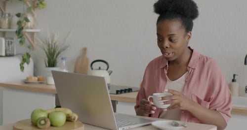 Young Woman Video Conferencing in Sunny Kitchen