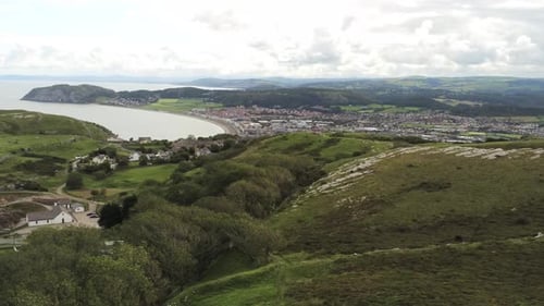 Aerial view across vast scenic Welsh mountain valley lush Llandudno coastline slow pull back