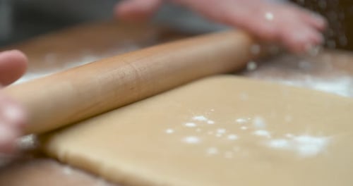 Rolling Pin Smooths Dough Covered with Flour