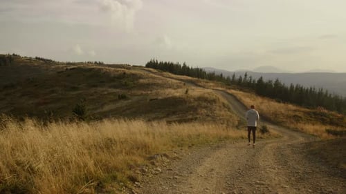 Young Man Exercising in Natural Landscape. Back View Athletic Guy Jogging On