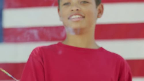 Smiling Boy Holding Sparkler in front of American Flag