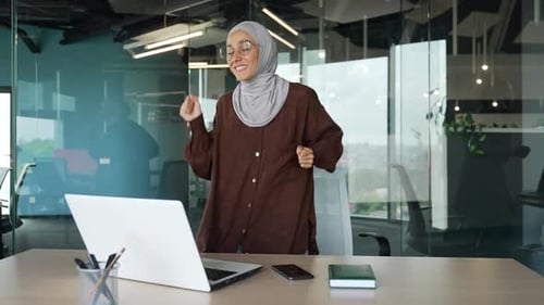 Excited Woman Dancing at Desk in Modern Office