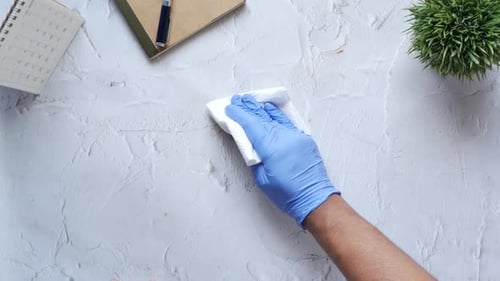 Gloved Hand Cleans Stain on Office Desk