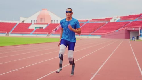 Asian para-athlete with prosthetic blades warms up body in the stadium.
